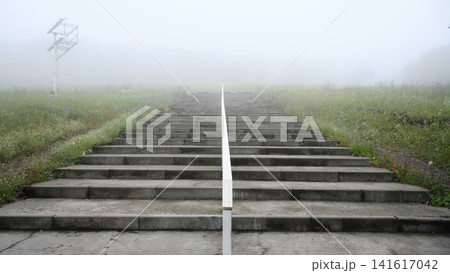 Concrete stairs ascending into dense fog. Empty outdoor steps with white handrail leading to the unknown, old stairway in mist. Copy space for text Concrete stairs ascending into dense fog. Empty outdoor steps with white handrail leading to the unknown, old stairway in mist. Copy space for text 141617042