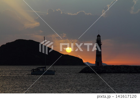 Seascape at sunshine. Lighthouse and sailings on the coast. Seaside town of Turgutreis and spectacular sunshine Seascape at sunshine. Lighthouse and sailings on the coast. Seaside town of Turgutreis and spectacular sunshine 141617120