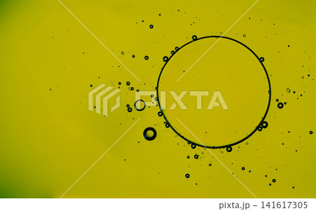Yellow liquid with dark oil drops and bubbles creating an abstract pattern Yellow liquid with dark oil drops and bubbles creating an abstract pattern 141617305