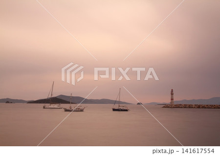 Seascape at sunshine. Lighthouse and sailings on the coast. Seaside town of Turgutreis and spectacular sunshine Seascape at sunshine. Lighthouse and sailings on the coast. Seaside town of Turgutreis and spectacular sunshine 141617554