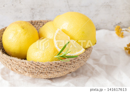 Fresh yellow lemons with rosemary sprigs in basket Fresh yellow lemons with rosemary sprigs in basket 141617613