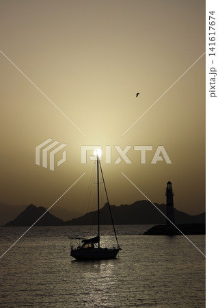 Seascape at sunshine. Lighthouse and sailings on the coast. Seaside town of Turgutreis and spectacular sunshine Seascape at sunshine. Lighthouse and sailings on the coast. Seaside town of Turgutreis and spectacular sunshine 141617674