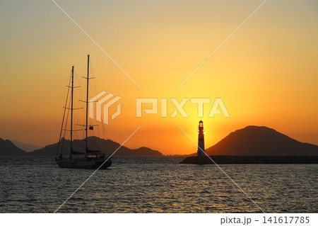Seascape at sunshine. Lighthouse and sailings on the coast. Seaside town of Turgutreis and spectacular sunshine Seascape at sunshine. Lighthouse and sailings on the coast. Seaside town of Turgutreis and spectacular sunshine 141617785