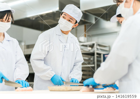 魚を調理するコックコート姿の男女スタッフ(調理師・料理人・生鮮市場・食品加工) 魚を調理するコックコート姿の男女スタッフ(調理師・料理人・生鮮市場・食品加工) 141619559
