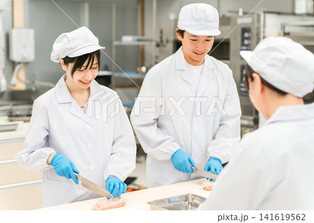 魚を調理するコックコート姿の男女スタッフ(調理師・料理人・生鮮市場・食品加工) 魚を調理するコックコート姿の男女スタッフ(調理師・料理人・生鮮市場・食品加工) 141619562