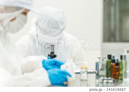 顕微鏡を見る薬品工場,製薬会社で薬品開発をするクリーンスーツを着たスタッフ 顕微鏡を見る薬品工場,製薬会社で薬品開発をするクリーンスーツを着たスタッフ 141619887