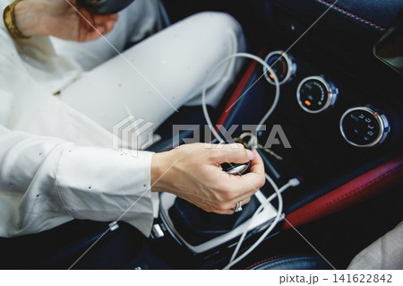 High-angle shot of a woman's hand holding a gear shifter inside a modern sport car console with climate control knobs. 141622842