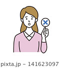 バツのプレートを持って不正解を示す残念そうな表情の若い女性 141623097