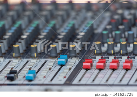 Closeup of professional audio mixing console colorful faders knobs sliders for sound engineering music production broadcasting recording live events Closeup of professional audio mixing console colorful faders knobs sliders for sound engineering music production broadcasting recording live events 141623729