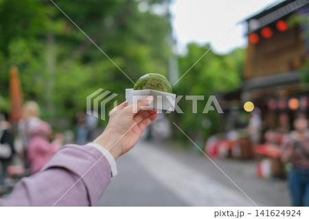 東京のレトロな観光地(深大寺近くの公道)で食べ歩きする女性が持つ饅頭のクローズアップ 東京のレトロな観光地(深大寺近くの公道)で食べ歩きする女性が持つ饅頭のクローズアップ 141624924