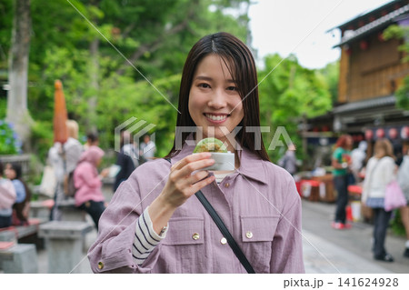 東京のレトロな観光地（深大寺近くの公道）で食べ歩きする女性が持つ饅頭のクローズアップ 141624928