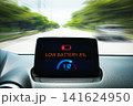 Dashboard display of an electric vehicle showing a low battery warning sign 141624950