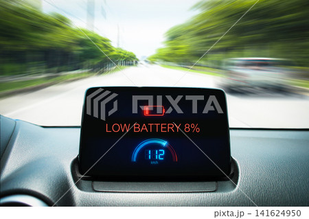Dashboard display of an electric vehicle showing a low battery warning sign Dashboard display of an electric vehicle showing a low battery warning sign 141624950
