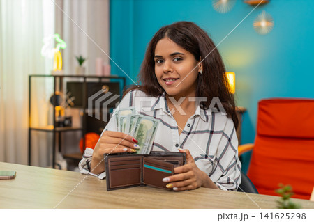 Indian rich woman counting dollars cash placing bills into wallet feeling satisfied, proud wealth Indian rich woman counting dollars cash placing bills into wallet feeling satisfied, proud wealth 141625298