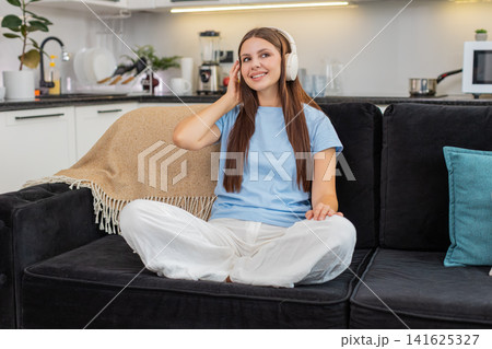Young woman relaxes with wireless headphones listens to favorite music rests eyes calm and peaceful Young woman relaxes with wireless headphones listens to favorite music rests eyes calm and peaceful 141625327