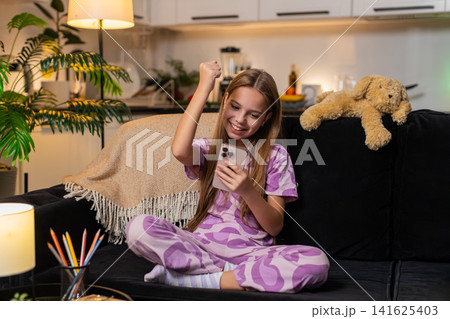 Teenager girl celebrates online game win on smartphone gets good news alert smiles cheers happy mood Teenager girl celebrates online game win on smartphone gets good news alert smiles cheers happy mood 141625403