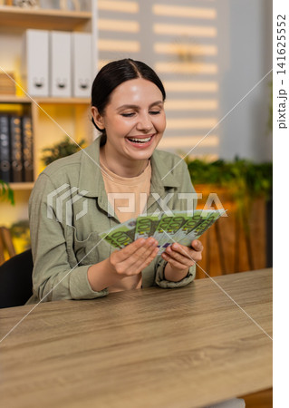 Young woman on home table counting euro cash feeling happy and satisfied with budget success indoors Young woman on home table counting euro cash feeling happy and satisfied with budget success indoors 141625552