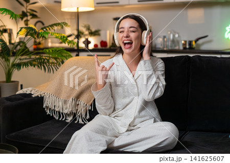 Young woman hears song in headphones starts seated dance rock moves laughs cheers yeah energy wild Young woman hears song in headphones starts seated dance rock moves laughs cheers yeah energy wild 141625607
