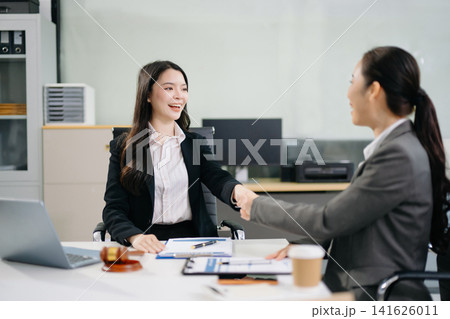 Asian lawyer and client shaking hands after signing a business contract in a modern office, symbolizing trust, legal agreement, partnership Asian lawyer and client shaking hands after signing a business contract in a modern office, symbolizing trust, legal agreement, partnership 141626011
