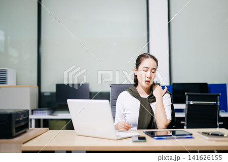 Asian woman feeling migraine head strain.Overworked businesswoman financier while working on laptop and tablet at office. Asian woman feeling migraine head strain.Overworked businesswoman financier while working on laptop and tablet at office. 141626155