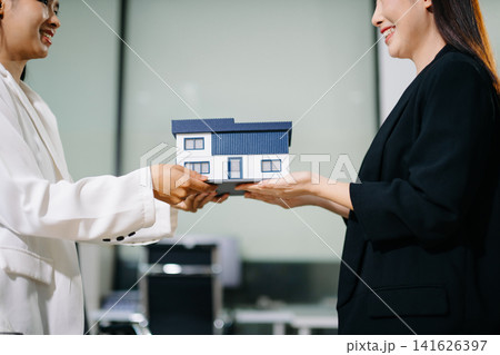 Real estate agent handing over house keys to a new homeowner, symbolizing property ownership transfer, successful home purchase and investment Real estate agent handing over house keys to a new homeowner, symbolizing property ownership transfer, successful home purchase and investment 141626397