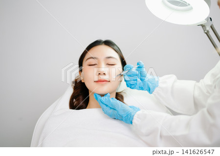 Doctor consulting patient in beauty clinic, skincare analysis, aesthetic treatment planning, professional advice, clean medical setting, modern cosmetic care for healthy skin. Doctor consulting patient in beauty clinic, skincare analysis, aesthetic treatment planning, professional advice, clean medical setting, modern cosmetic care for healthy skin. 141626547