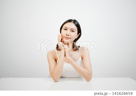 Asian woman with radiant skin posing in a clean white studio. Natural beauty, skincare, wellness and self-care concept with copy space for branding. 141626659