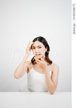 Asian woman with radiant skin posing in a clean white studio. Natural beauty, skincare, wellness and self-care concept with copy space for branding. Asian woman with radiant skin posing in a clean white studio. Natural beauty, skincare, wellness and self-care concept with copy space for branding. 141626673