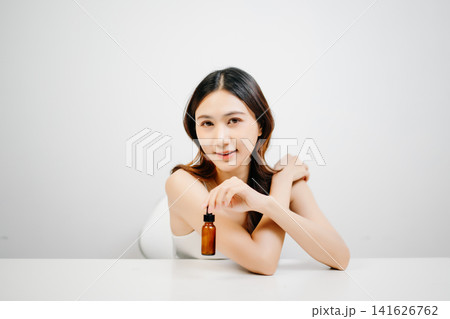 Asian woman holding serum with clean minimal aesthetic, glowing skin and skincare routine concept for cosmetic advertising, branding and product promotion Asian woman holding serum with clean minimal aesthetic, glowing skin and skincare routine concept for cosmetic advertising, branding and product promotion 141626762