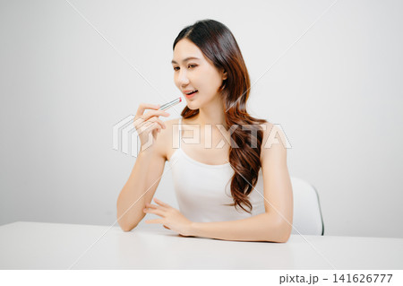 Asian woman holding lipstick with clean minimal style, soft light and natural beauty look for cosmetic advertising, makeup promotion Asian woman holding lipstick with clean minimal style, soft light and natural beauty look for cosmetic advertising, makeup promotion 141626777