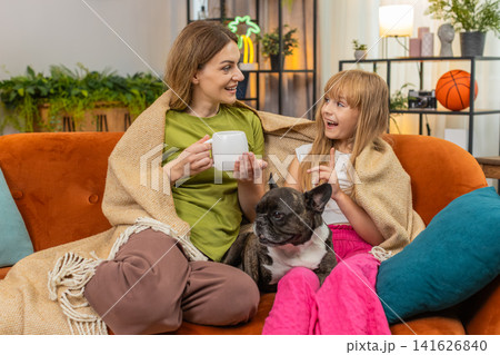Mother daughter dog share tea and blanket relax together cozy rest hug smile comfort family evening Mother daughter dog share tea and blanket relax together cozy rest hug smile comfort family evening 141626840