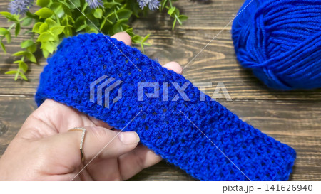 A blue thread pattern on a wooden background. Knitting tutorial and sample of the finished piece. 141626940