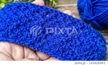 A blue thread pattern on a wooden background. Knitting tutorial and sample of the finished piece. 141626941