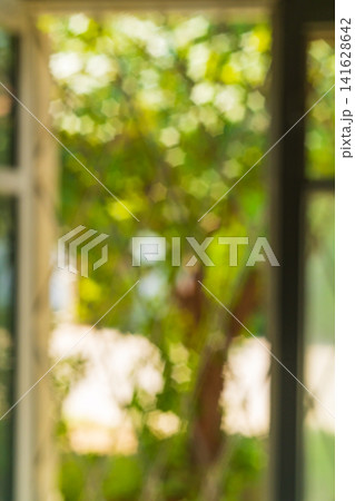 Vertical beautiful blurred photo background overlooking defocused window frames, behind which are trees with a bokeh effect in yellow green with polygonal stars. Soft focused, no focus Vertical beautiful blurred photo background overlooking defocused window frames, behind which are trees with a bokeh effect in yellow green with polygonal stars. Soft focused, no focus 141628642