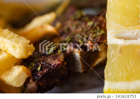 Close up of lamb chops with french fries and lemon slice an appetizing meal 141628751