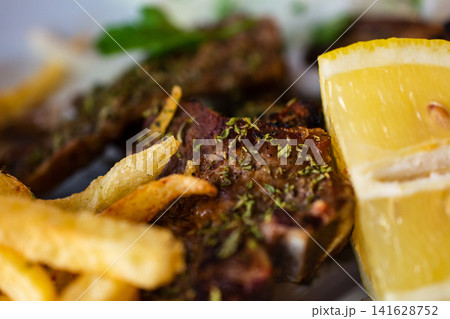 Grilled lamb chops with crispy french fries and fresh lemon slice making a delicious meal Grilled lamb chops with crispy french fries and fresh lemon slice making a delicious meal 141628752