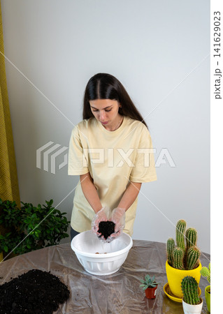 Young Woman Holding Soil in Hands Over Bowl for Cactus Repotting Young Woman Holding Soil in Hands Over Bowl for Cactus Repotting 141629023
