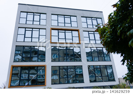 Modern architecture displayed through reflective windows captures urban life in a lively city setting during a cloudy afternoon Modern architecture displayed through reflective windows captures urban life in a lively city setting during a cloudy afternoon 141629259