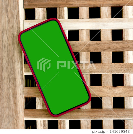 Angled smartphone mockup with green screen on a wooden lattice background. Modern mobile template with copy space for app design and advertising. Blank phone display for branding Angled smartphone mockup with green screen on a wooden lattice background. Modern mobile template with copy space for app design and advertising. Blank phone display for branding 141629548