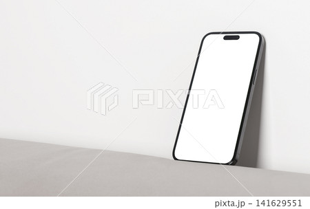 Blank smartphone leans against a wall on a minimal surface. Angled mobile phone mockup with copy space and clean studio lighting. Ideal for app advertising, UI design, and product 141629551