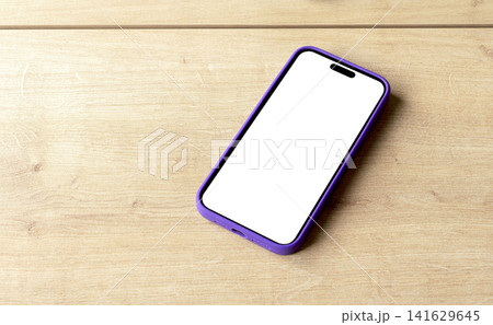 Phone mockup with a blank white screen and purple frame lies diagonally on a wooden cutting board. Phone mockup with a blank white screen and purple frame lies diagonally on a wooden cutting board. 141629645