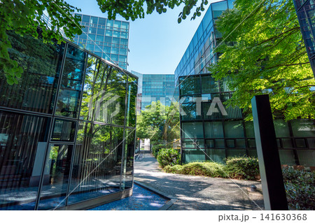 Modern glass office buildings with trees at Stieglmaierplatz in Munich, Bavaria, contemporary corporate architecture with reflective facades and green courtyard under blue sky Modern glass office buildings with trees at Stieglmaierplatz in Munich, Bavaria, contemporary corporate architecture with reflective facades and green courtyard under blue sky 141630368