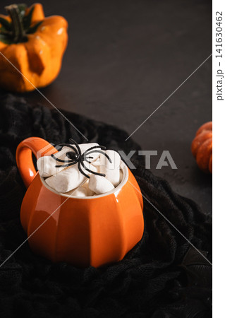 Halloween pumpkin mug with marshmallows and spider on black background Halloween pumpkin mug with marshmallows and spider on black background 141630462