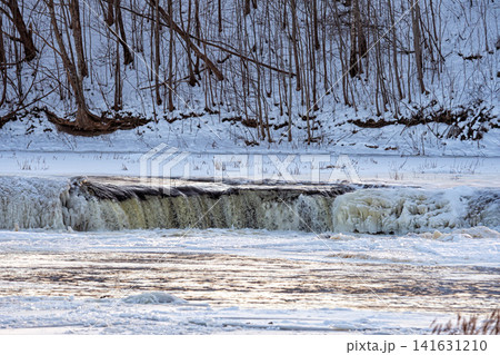 Water flows over a frozen edge in a cold winter setting by a river Water flows over a frozen edge in a cold winter setting by a river 141631210