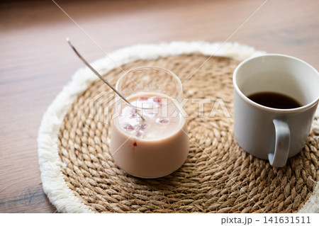 Refreshing homemade iced coffee with frozen cherry juice cubes served beside a cup of black coffee. Cozy home preparation concept with natural light and rustic styling. 141631511