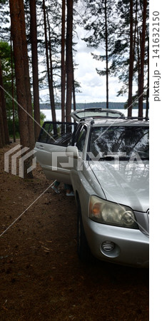 Car parked in the forest with lake in the background during daylight Car parked in the forest with lake in the background during daylight 141632150
