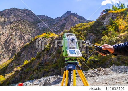 Surveying Instrument in Mountainous Landscape with Handheld Radio 141632501