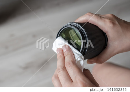 Person cleaning photography lens glass with a soft cleaning cloth Person cleaning photography lens glass with a soft cleaning cloth 141632853