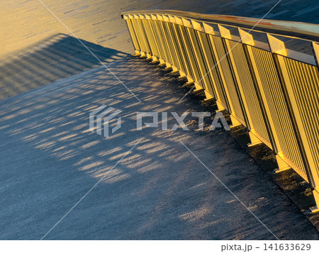 Golden sunlight casts patterned shadows from metal railing Golden sunlight casts patterned shadows from metal railing 141633629