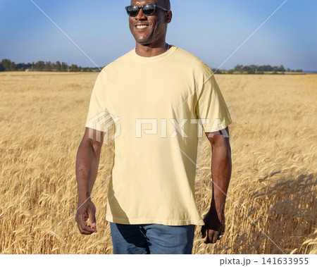 Blank light yellow t-shirt mockup on black man in wheat field at sunset, front view with copy space Blank light yellow t-shirt mockup on black man in wheat field at sunset, front view with copy space 141633955